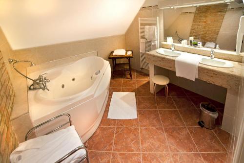 a bathroom with a tub and two sinks at Château des Monthairons Hôtel Restaurant GastroMaison Spa privatif in Les Monthairons