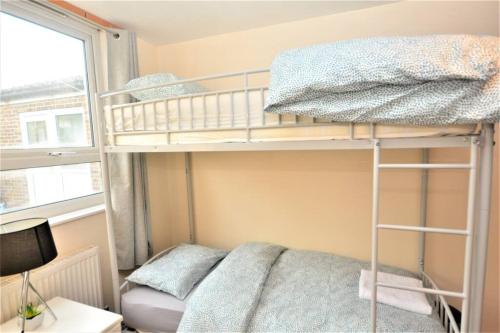 a bunk bed in a small room with a window at Spacious 2Bedroom condo with Patio by Excel Centre in London