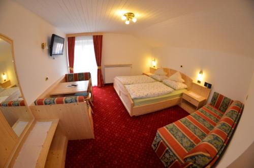 a hotel room with two beds and a table and chairs at Garni Ossi in Santa Cristina in Val Gardena