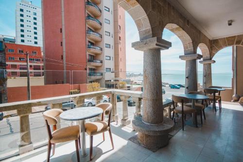 uma varanda com mesas e cadeiras e vista para o oceano em SEC Hotel em Mar del Plata