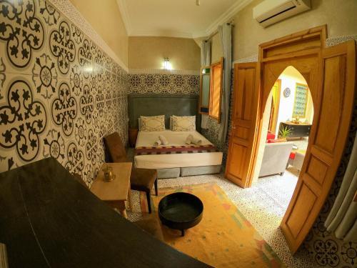a bedroom with a bed and a table in a room at Riad Inaka in Marrakech