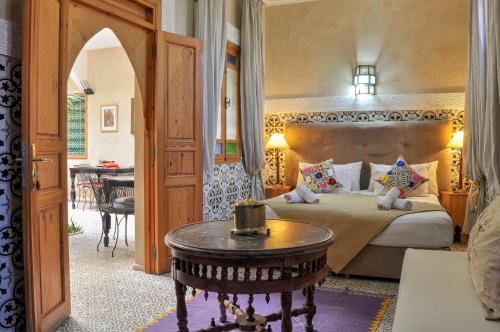 a bedroom with a bed and a table in a room at Riad Inaka in Marrakech
