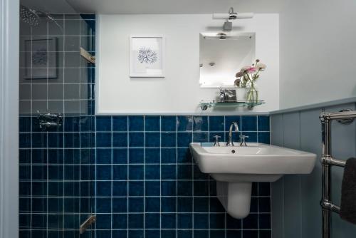 a blue tiled bathroom with a sink and a mirror at Navas Nook in Falmouth