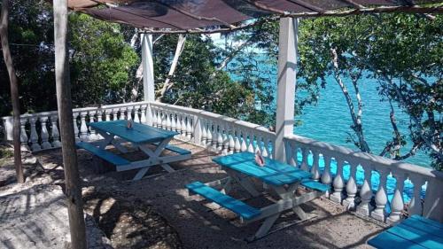altana z niebieskimi stołami i krzesłami obok wody w obiekcie Veleando Ando Cabañas w mieście Bacalar
