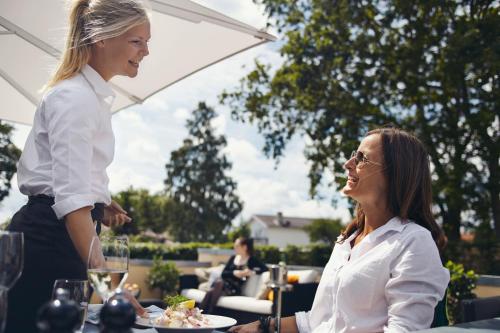 a woman standing next to a woman sitting at a table at Molskroen Strandhus in Ebeltoft