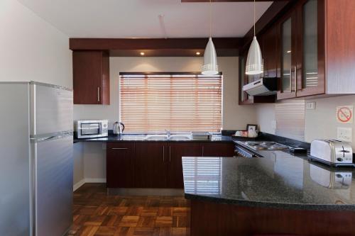 a kitchen with a stainless steel refrigerator and wooden cabinets at 10 on Cape Self Catering Apartments in Port Elizabeth