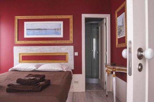 a bedroom with red walls and a bed with towels on it at Legendary Bay Apartamento Temático in Seixal