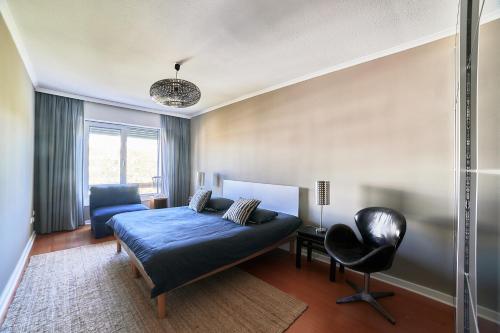 ein Schlafzimmer mit einem Bett und einem Stuhl in der Unterkunft Charming Deluxe Apartment in Oeiras