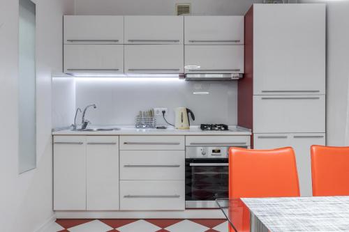 a kitchen with white cabinets and orange chairs at Apartment Kiev House in Kyiv