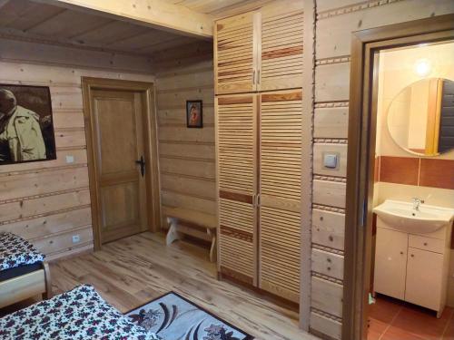 a bathroom with wooden walls and a sink at Luksusowa Willa w sercu Gorców in Ochotnica Górna