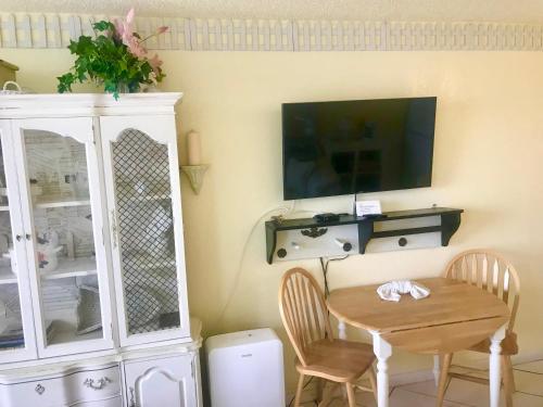 a dining room with a table and a tv on a wall at Ocean Waves - Ocean Front at Symphony Beach Club! in Ormond Beach