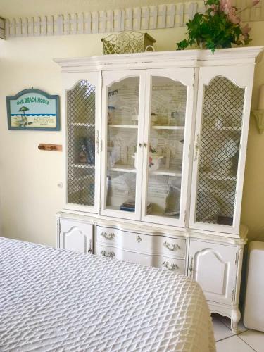 a white cabinet with glass doors in a bedroom at Ocean Waves - Ocean Front at Symphony Beach Club! in Ormond Beach