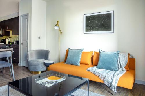 a living room with an orange couch and a table at Placemakr Music Row - Vanderbilt in Nashville
