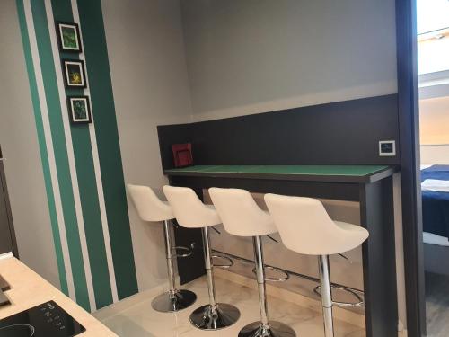 a room with a bar with white stools at Kaposvár Apartman in Kaposvár