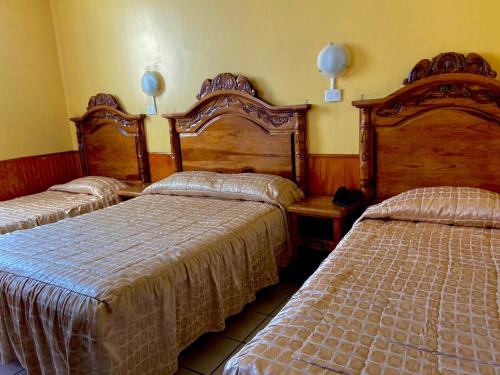 杜蘭戈的住宿－Hotel Nuevo Centenario，一间卧室设有两张床,墙上有两盏灯。