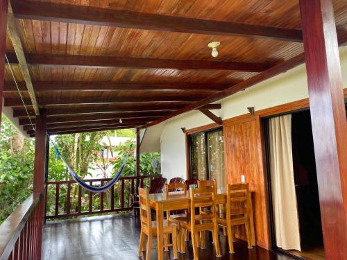 a dining room with a table and chairs on a balcony at Cabaña Ara Macao Lodge in Drake