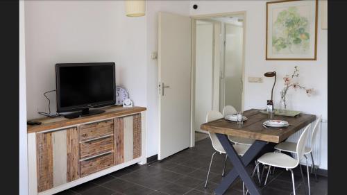 een woonkamer met een tv en een tafel met stoelen bij Huinerhofje 2 in Putten