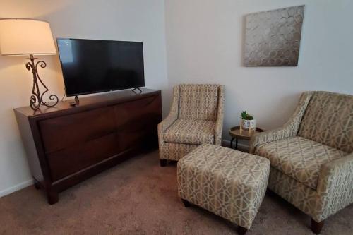salon z 2 krzesłami i telewizorem z płaskim ekranem w obiekcie Trenton's Apartment on First w mieście Trenton
