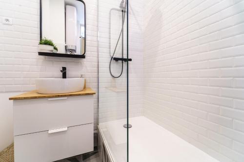 une salle de bain blanche avec un lavabo et une douche dans l'établissement Parisuites Central Canal Saint Martin Chic & Design & Cosy, à Paris