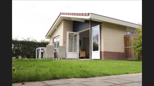 a small house with a porch and chairs in a yard at Huinerhofje 2 - Vrijstaand met grote omheinde tuin, rust, privacy en nabij bossen in Putten