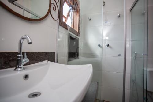 a bathroom with a sink and a mirror and a shower at Hotel Bandeirantes - Unidade Centro in Cachoeira do Campo