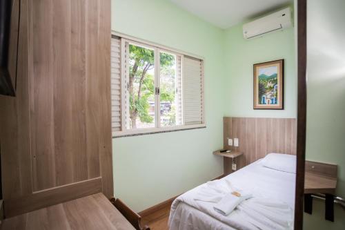 a bedroom with a bed and a window at Hotel Bandeirantes - Unidade Centro in Cachoeira do Campo