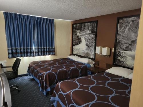 two beds in a hotel room with blue curtains at Super 8 North Red Deer in Red Deer