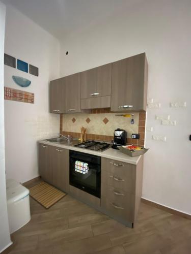 a kitchen with a stove and cabinets and a toilet at La casa di sara in Nuoro