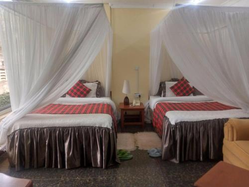 a bedroom with two beds with curtains and a window at Karibu Heritage House in Arusha