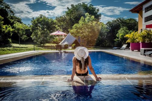 梅爾加的住宿－Mangoo Glamping，坐在游泳池的戴帽子的女人