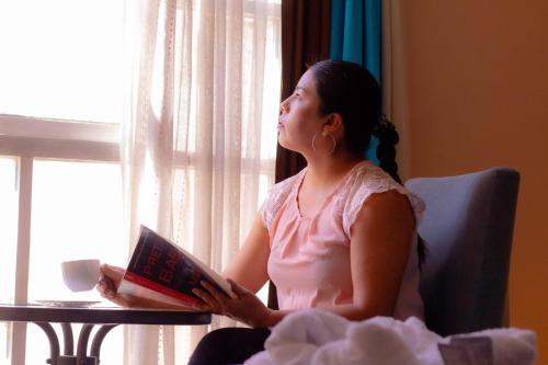 a woman sitting in a chair reading a book at Chikan Hoteles in Arequipa