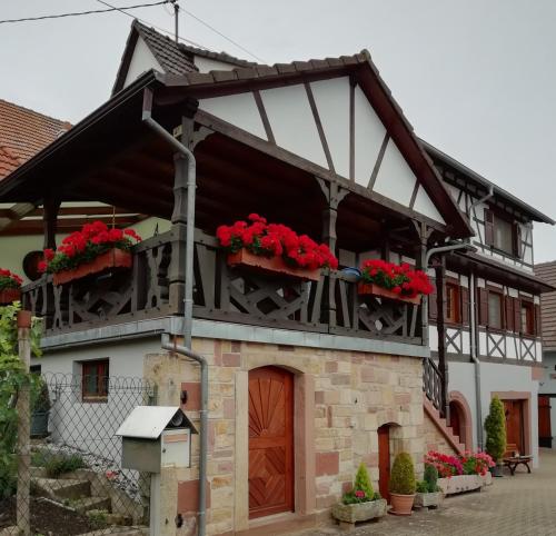 ein Haus mit roten Blumen auf dem Balkon in der Unterkunft Gîte HAURY in Cleebourg