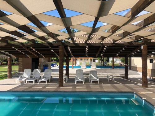 a patio with chairs and a swimming pool with a roof at Posada Campestre Tasquillo in Tasquillo