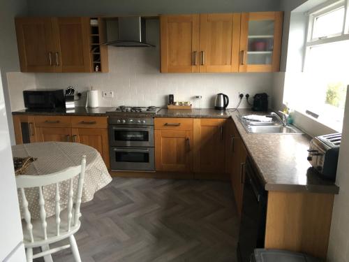 a kitchen with wooden cabinets and a table and a sink at Number One - Fully Equipped Self Catering Four Bedroom House next to Dunedin, 15 mins to Spurn, 20 mins to Saltend, 12 mins to Easington in Patrington