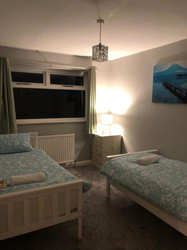 a bedroom with two beds and a window and a lamp at Number One - Fully Equipped Self Catering Four Bedroom House next to Dunedin, 15 mins to Spurn, 20 mins to Saltend, 12 mins to Easington in Patrington