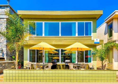 una casa con tavoli, sedie e ombrelloni gialli di Surf N Sand 1 & 2 a Newport Beach