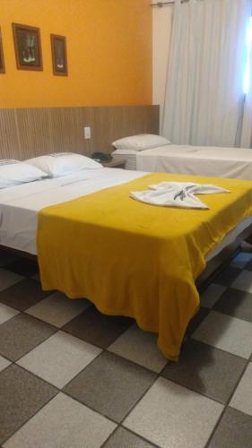 a room with two beds with a yellow blanket on it at Hotel Enseada de Ponta Negra in Natal