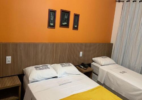 two beds in a room with orange walls at Hotel Enseada de Ponta Negra in Natal