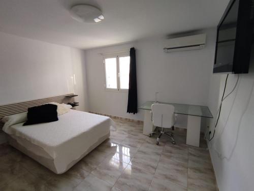a white bedroom with a bed and a desk at Habitación en Casa Denube in Las Playas