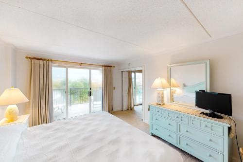 a bedroom with a bed and a mirror and a television at Nauti by Nature in Nags Head