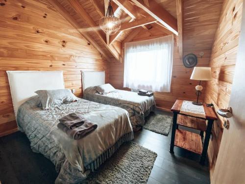 a bedroom with two beds in a log cabin at Cabaña frente al lago Meliquina in Villa Meliquina