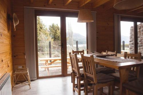 a dining room with a table and chairs and a large window at Cabaña frente al lago Meliquina in Lago Meliquina