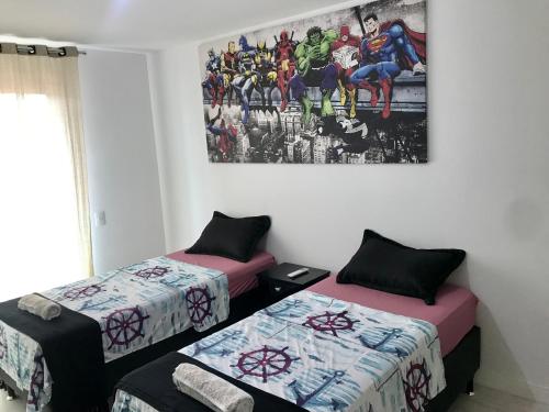 a room with two beds and a painting on the wall at Praia dos Anjos Residence Clube - O melhor de Arraial do Cabo in Arraial do Cabo