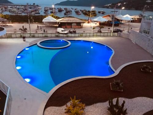 a large blue swimming pool on top of a building at Praia dos Anjos Residence Clube - O melhor de Arraial do Cabo in Arraial do Cabo