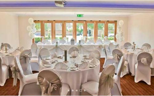 a banquet hall with white tables and chairs at The Boleyn Hotel in Staines