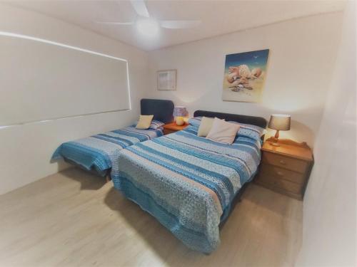 a bedroom with two beds and a table with a lamp at Moondara Unit 2 21 Bulcock Beach Esplanade Bulcock Beach in Caloundra
