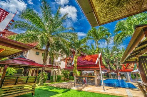an exterior view of a house with a pool and palm trees at Sai Rougn Residence - SHA Extra Plus in Patong Beach