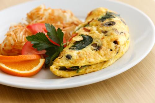 a plate of food with an omelet and vegetables at Holiday Inn & Suites Makati by IHG in Manila