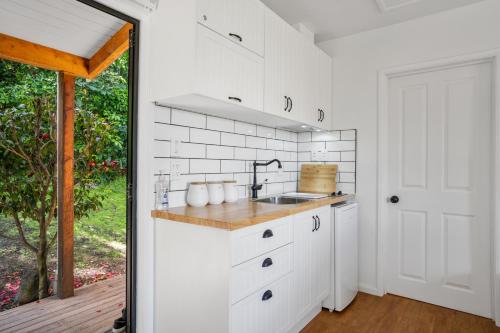 een keuken met witte kasten en een wastafel bij Woodside - Akaroa Holiday Cottage in Akaroa