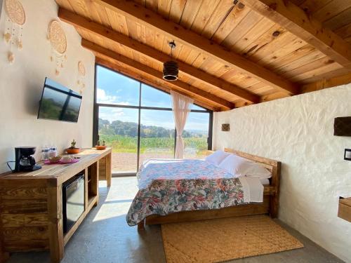 a bedroom with a bed and a desk and a large window at Las Cabañas Mavoro in Jocotitlán